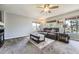 Comfortable living room with a leather sofa, large windows, and neutral-toned carpet at 5316 S Rome St, Aurora, CO 80015