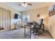 Functional office with a ceiling fan, natural light, carpeted floor, and a mounted television at 5316 S Rome St, Aurora, CO 80015