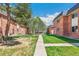 Exterior perspective of brick townhomes featuring landscaped lawns, mature trees, and a sidewalk at 3685 W Union Ave, Denver, CO 80236