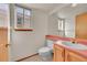 Cozy bathroom with light pink counter, wood cabinets, and a window for natural lighting at 18736 E Powers Pl, Aurora, CO 80015