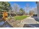 Spacious backyard featuring a play structure, artificial grass, and mature trees at 10273 Bentwood Ln, Highlands Ranch, CO 80126
