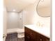 Bathroom featuring a dark wood vanity, gold fixtures, round mirror and step-in shower at 5882 W Chestnut Ave, Littleton, CO 80128
