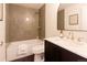 Modern bathroom featuring a sleek vanity with black cabinets, gold fixtures, and stylish arched mirror at 5882 W Chestnut Ave, Littleton, CO 80128