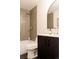 Modern bathroom featuring a sleek vanity with black cabinets, gold fixtures, and stylish arched mirror at 5882 W Chestnut Ave, Littleton, CO 80128