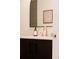 Modern bathroom featuring a sleek vanity with black cabinets, gold fixtures, and stylish arched mirror at 5882 W Chestnut Ave, Littleton, CO 80128
