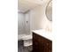 Bathroom featuring a dark wood vanity, gold fixtures, round mirror and step-in shower at 5882 W Chestnut Ave, Littleton, CO 80128