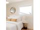 Bright bedroom featuring plush white bedding, round mirror, and a view from a window at 5882 W Chestnut Ave, Littleton, CO 80128