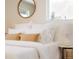 Bright bedroom featuring plush white bedding, round mirror, and a view from a window at 5882 W Chestnut Ave, Littleton, CO 80128