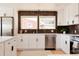 Bright eat-in kitchen with white cabinets, stainless appliances, dark backsplash, and an island with barstool seating at 5882 W Chestnut Ave, Littleton, CO 80128