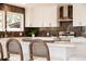Bright eat-in kitchen features white cabinets, stainless appliances, dark backsplash, and an island with barstool seating at 5882 W Chestnut Ave, Littleton, CO 80128