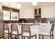 Bright eat-in kitchen with white cabinets, stainless appliances, dark backsplash, and island with barstool seating at 5882 W Chestnut Ave, Littleton, CO 80128