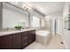 Bathroom featuring double vanity, soaking tub, and neutral tile throughout at 6723 Raritan Dr, Denver, CO 80221