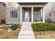 Inviting covered front porch with a red door and small seating area at 6723 Raritan Dr, Denver, CO 80221
