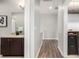 Hallway with wood floors that connects to a bathroom with vanity and a tiled wall with gray cabinets at 6723 Raritan Dr, Denver, CO 80221