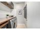 Laundry room with wooden countertop, white subway tile backsplash, washer, dryer, and storage space at 6723 Raritan Dr, Denver, CO 80221