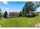 Large backyard with lush green grass, mature trees, and privacy fence at 69 N Ranch Rd, Littleton, CO 80127