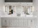 Elegant bathroom featuring double sinks, sleek gray cabinetry, quartz countertops, and sophisticated marble backsplash at 16267 W 59Th Pl, Golden, CO 80403