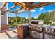 Outdoor kitchen with built-in stainless steel grill, brick siding, and wooden deck overlooking mountains at 16267 W 59Th Pl, Golden, CO 80403