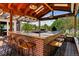 Outdoor kitchen area with brick bar, stools, built-in grill, skylights, and wood beam construction at 16267 W 59Th Pl, Golden, CO 80403
