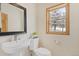 Powder room featuring a pedestal sink, toilet, modern fixtures and window with wooded view at 342 Brook Cir, Boulder, CO 80302