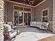 Covered outdoor patio with stone accents, comfortable seating, ceiling fan, and sliding glass doors at 6970 E Lake Dr, Centennial, CO 80111