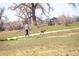 A person walks their dog on a community walking path surrounded by trees and grass at 13742 Valentia St, Thornton, CO 80602