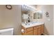 A neutral bathroom featuring a wide mirror with vanity lighting and a sink with wood cabinets at 10532 Madison St, Thornton, CO 80233