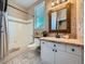 Bright bathroom with white vanity, stone accent wall, travertine countertops, and shower-tub combination at 18971 E Pinewood Dr, Aurora, CO 80016