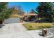 Well-maintained home featuring a spacious driveway and a charming front porch, complemented by mature trees and landscaping at 590 S Troy St, Aurora, CO 80012