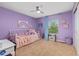Charming bedroom with purple walls, ceiling fan, and window overlooking a tree-lined street at 24702 E Ontario Dr, Aurora, CO 80016