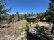 Charming two-story cabin with a green roof surrounded by mature trees and blue skies at 72 Rudi W Ln, Golden, CO 80403