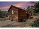 Charming cabin featuring two garage doors and a quaint wooden staircase with beautiful sunset sky at 72 Rudi W Ln, Golden, CO 80403