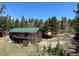 Charming cabin with a green roof, wrap-around balcony and beautiful forest surroundings on a sunny day at 72 Rudi W Ln, Golden, CO 80403