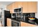 Modern kitchen with stainless steel appliances, black countertops, and light wood cabinets at 1700 Bassett St # 1111, Denver, CO 80202