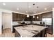 Modern kitchen featuring dark wood cabinets, granite countertops, stainless steel appliances, and an island with bar seating at 960 S De Gaulle Ct, Aurora, CO 80018
