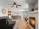 Open-concept living room with a fireplace, dark sofa, ceiling fan, and wood-look flooring at 896 Willow Dr, Brighton, CO 80603