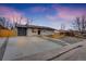 Ranch style home with a newly paved driveway and modern gray garage door at 1061 Elbert St, Denver, CO 80221