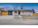 Newly renovated Ranch home with gray garage door and wood fence at 1061 Elbert St, Denver, CO 80221