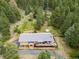 Aerial view of brick home with large deck, surrounded by lush trees and a stone retaining wall at 7815 Armadillo Trl, Evergreen, CO 80439