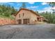 A brick house featuring a two-car garage and an expansive driveway is surrounded by nature at 7815 Armadillo Trl, Evergreen, CO 80439