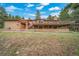 A brick home showcases an expansive deck and inviting front entry amid a verdant landscape at 7815 Armadillo Trl, Evergreen, CO 80439