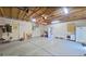 A large, unfinished garage with storage, exposed beams, and a 
