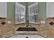 Corner kitchen sink with granite countertops, designer backsplash, and natural light from two windows at 16453 Homestead Ct, Parker, CO 80134
