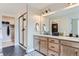 Bathroom with vanity, wooden cabinets, a large mirror, and walk-in shower with black accents at 2475 W 69Th Pl, Denver, CO 80221