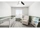 Cozy Bedroom featuring a white crib, a comfortable armchair, and stylish wallpaper at 21925 E 44Th Pl, Aurora, CO 80019