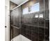 Bathroom shower with dark tile, glass door, built-in niche, and a window for natural light at 21925 E 44Th Pl, Aurora, CO 80019