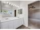 Bright bathroom featuring a double vanity, large mirror and a connecting door to the main bedroom at 9147 W Rockland Pl, Littleton, CO 80128