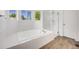 Bright bathroom features a soaking tub with jets, a glass-enclosed shower, and wood floors at 9147 W Rockland Pl, Littleton, CO 80128