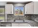 Close-up of the kitchen sink area showcasing the granite countertop and attractive mosaic backsplash at 9147 W Rockland Pl, Littleton, CO 80128