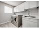 Functional laundry room equipped with a sink, cabinets, and modern washer and dryer at 9147 W Rockland Pl, Littleton, CO 80128